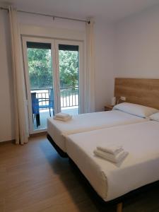 two beds in a hotel room with a balcony at Villa El Encinar de Noja in Noja