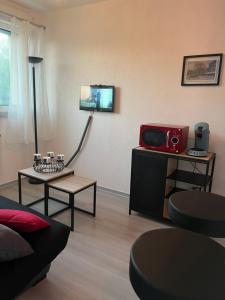 a living room with a couch and a tv on a wall at Cocon Accès facile Parking Gratuit in Belfort