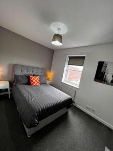 a bedroom with a bed with a red pillow and a window at Renfrew Home from Home in Renfrew