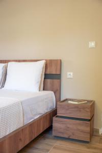 a bed with a wooden headboard and a wooden night stand at Μελίτη Pelion Luxury Living in Zagora