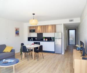 卡诺海滩SOUTH-OF-FRANCE T2 neuf haut de gamme, climatisé, parking gratuit, 2eme ligne balcon的一间厨房和一间带桌椅的客厅