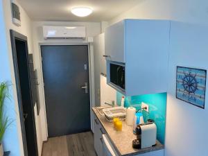 une petite cuisine avec un comptoir et une porte bleue dans l'établissement Málna Apartman Juventus, à Balatonföldvár
