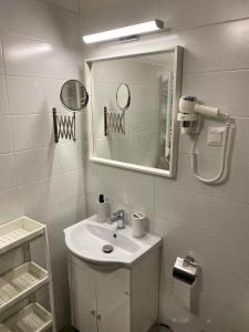 La salle de bains blanche est pourvue d'un lavabo et d'un miroir. dans l'établissement Málna Apartman Juventus, à Balatonföldvár