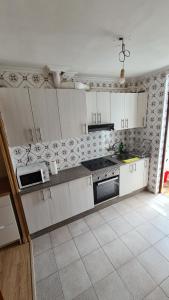 Il comprend une cuisine avec des placards blancs et du carrelage. dans l'établissement Precioso apartamento en Ferrol, à Ferrol