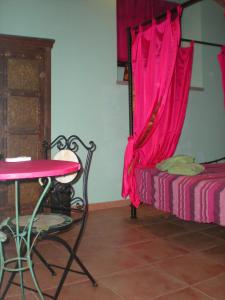 ローマにあるShiva B&Bのテーブルとピンクのカーテンが付いたベッドが備わる客室です。