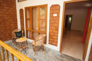 a porch with two chairs and a table and a door at Ashiyana Cliff and Beach Resort in Varkala