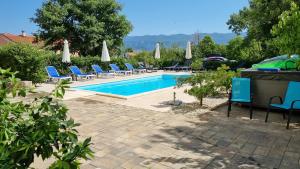 a swimming pool with blue chairs and umbrellas at Apartments Bellator in Šilo