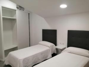 two beds in a room with white walls at Precioso apartamento vacaciones en zona Ramallosa in Baiona