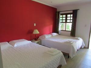 duas camas num quarto com paredes vermelhas em Pousada Ipitanga IV em Lauro de Freitas