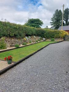 a garden with a stone hedge and a walkway at Traditional old style farmhouse in Coolvally