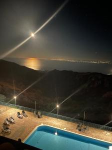 a swimming pool with a view of the ocean at night at Al Dolmen in Monte SantʼAngelo