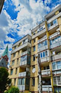Un edificio amarillo con un árbol delante. en Apartman Sky, en Sarajevo