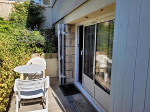 een patio met een tafel en stoelen aan de zijkant van een huis bij logement à 50 m de la mer ! in Hermanville-sur-Mer