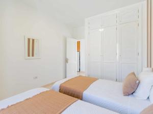 een witte slaapkamer met 2 bedden en een kast bij Mahostly Apartamento Comillas SB in Arrecife