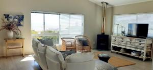a living room with white chairs and a flat screen tv at Hilton Cove Beach House in Melkbosstrand