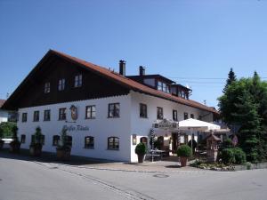 ein großes weißes Gebäude mit einem Schirm davor in der Unterkunft Landhotel Zahn's Weißes Rössle - ruhig schlafen- gut frühstücken - lecker essen in Dietmannsried