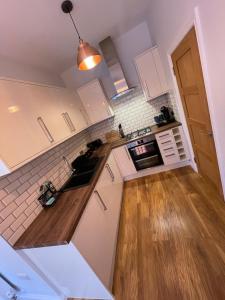 a kitchen with white cabinets and a wooden floor at Stylish One Bedroom Central Bournemouth Flat in Bournemouth