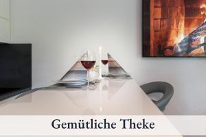 a white table with two glasses of wine on it at Relax-Apartment Biberach - Relax Massagesessel - Smart-TV 85 Zoll - voll ausgestattete Küche - High-Speed Internet - Arbeitsplatz mit Curved Monitor in Biberach an der Riß