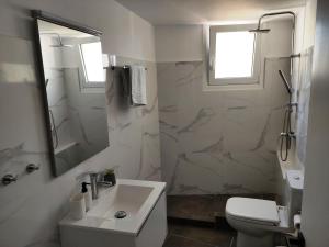 a white bathroom with a sink and a toilet at Karavela Street Apartment in Preveza
