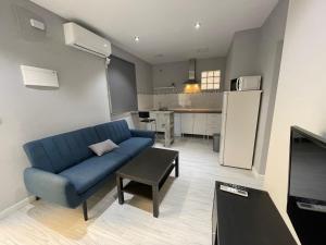 a living room with a blue couch and a kitchen at Villas Adrian in Jerez de la Frontera