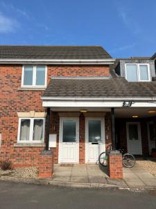 IbstockにあるThe Aldridge 2 Bedroom Apartment with FREE Parkingの白いドアと前に自転車があるレンガ造りの家