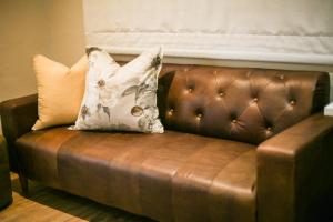 a brown leather couch with a pillow on it at Walmer Manor Guest House in Port Elizabeth