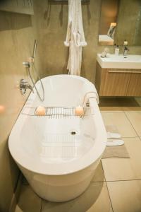 a white tub in a bathroom with a sink at Walmer Manor Guest House in Port Elizabeth