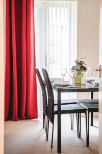 Snapos Apartments - Tudor Close في Carbrook: طاولة طعام مع كراسي وستارة حمراء