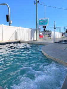 a pool of water next to a white fence at Aqua Blue Motel in Gold Coast