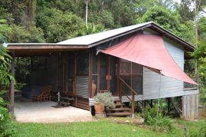 Una pequeña casa con un toldo rojo. en Palmwoods Eco Escape en Palmwoods