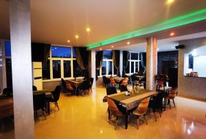 un restaurante con mesas, sillas y ventanas en Sunrise Hotel & Camping, en Struga