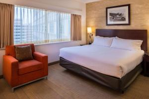 a hotel room with a bed and a chair at Sonesta Chicago O'Hare Airport Rosemont in Rosemont