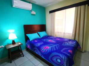 a blue bedroom with a bed and a window at Loky's Apartments La Fortuna in Fortuna
