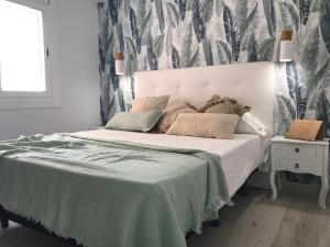een slaapkamer met een wit bed en een groene deken bij Panoramic sea view Lloret de Mar in Lloret de Mar
