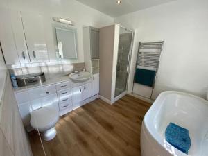 un bagno con vasca, lavandino e WC di Church Hall & Secret Garden Hideaway at Summer Hills Whitby a Whitby
