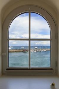 an arched window with a view of a harbor at Les Appartements d'Alexandre in Le Palais
