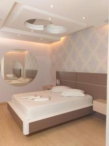 een slaapkamer met een wit bed en een ronde spiegel bij Motel Chevalier in Lages