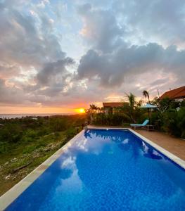 a swimming pool with a sunset in the background at Gara Gara Sea View in Nusa Penida