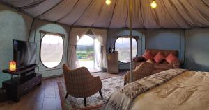 a bedroom with a tent with a bed and chairs at Glamping ILLARI Boutique in Paipa