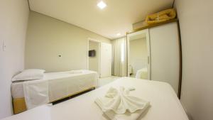 a white bedroom with two beds and a mirror at Viena Apart Hotel in Telêmaco Borba