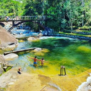 dos personas nadando en un río con un puente en Rancho São Carlos, en Itatiaia