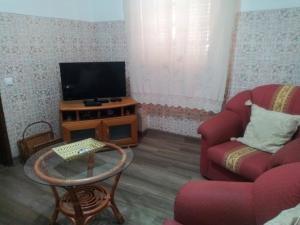 a living room with a tv and a couch and a table at Vivenda Becho in Alpalhão