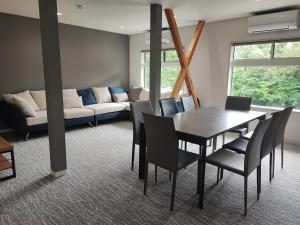 a dining room with a table and chairs and a couch at Hakuba Sunrise Apartments in Hakuba