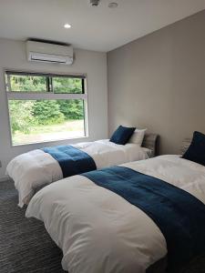 three beds in a room with a window at Hakuba Sunrise Apartments in Hakuba
