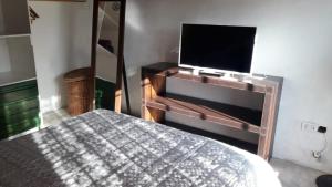 1 dormitorio con 1 cama y TV de pantalla plana en La Armonie de Chacras en Chacras de Coria