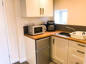 a kitchen with a counter with a microwave and a sink at Deers Leap, A modern new personal double bedroom holiday let in The Forest Of Dean in Blakeney