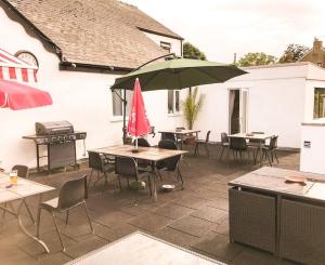 a patio with tables and chairs and an umbrella at Deers Leap, A modern new personal double bedroom holiday let in The Forest Of Dean in Blakeney