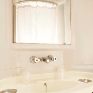 een witte badkamer met een wastafel en een raam bij Premiere Classe Niort Est La Creche in La Creche