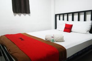 um quarto com uma cama grande com travesseiros vermelhos e brancos em RedDoorz at Jalan Somba Opu Losari em Macáçar