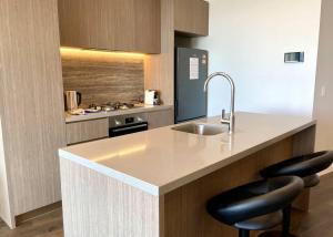 a kitchen with a sink and two bar stools at Luxury ocean skyline stunner 2beds apt 33F in Gold Coast